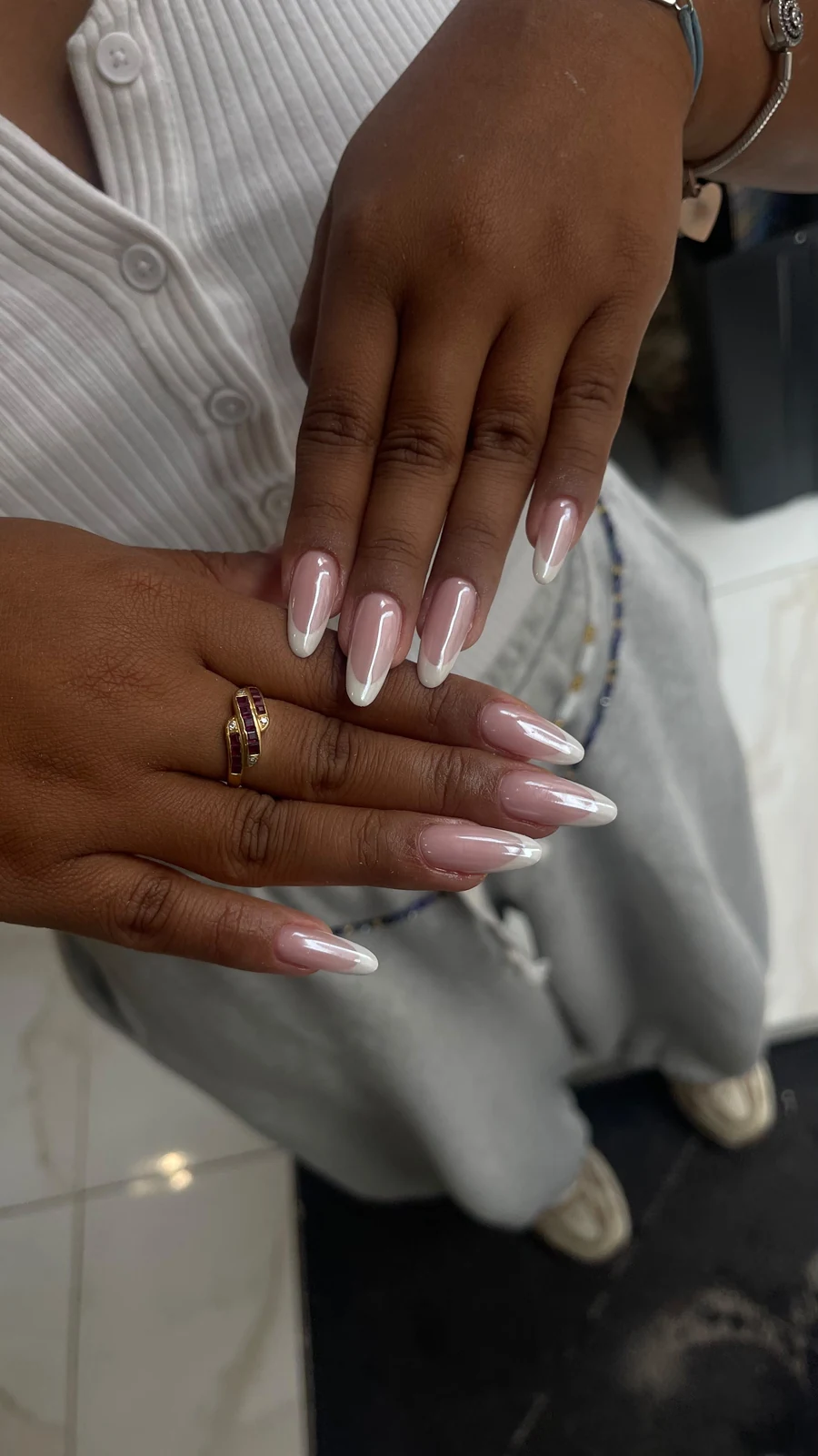 Deux mains avec une French blanche sur base rose, aux ongles en amande.
