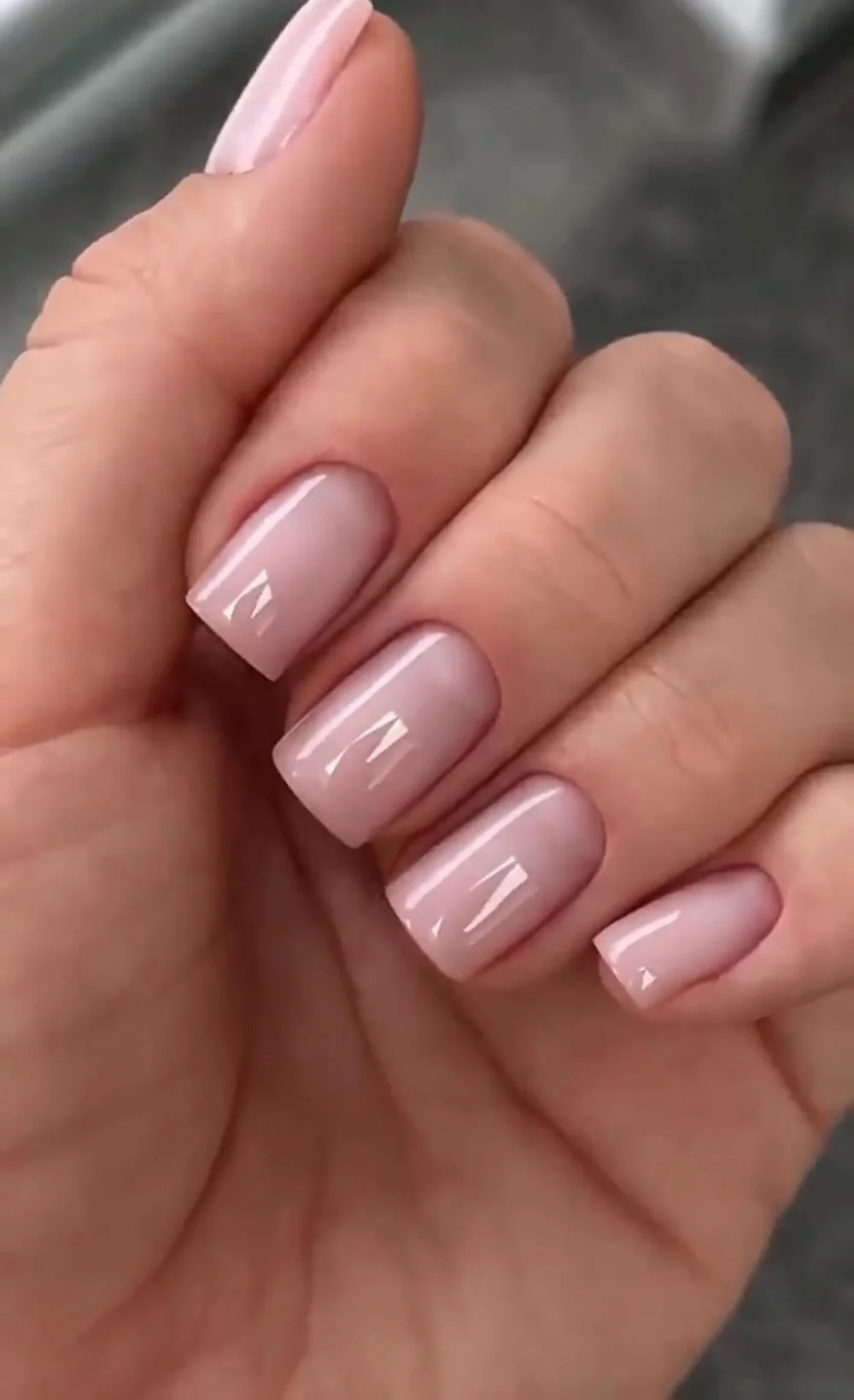 Ongles courts carrés aux angles arrondis, finition nude rosée brillante.